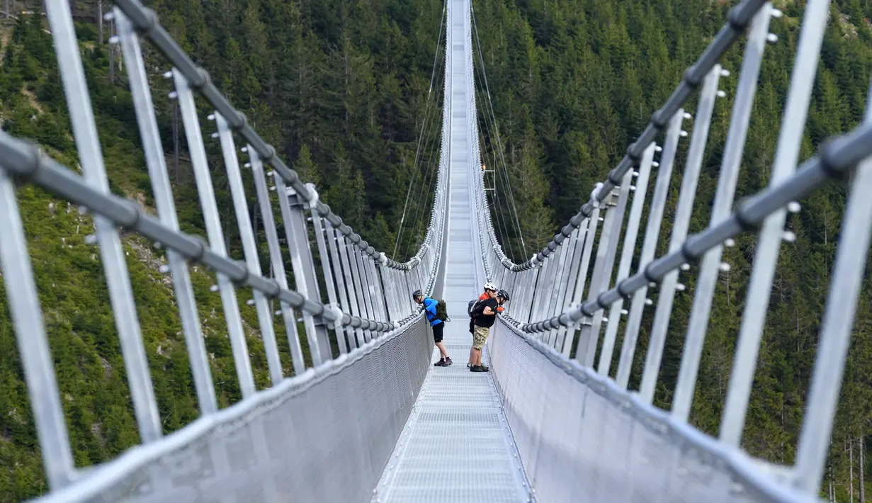 Orang-orang berdiri di jembatan gantung untuk pejalan kaki yang merupakan konstruksi terpanjang di dunia sehari sebelum pembukaan resminya di sebuah resor pegunungan di Dolni Morava, Republik Ceko, Kamis (12/5/2022). (AP Photo/Petr David Josek)