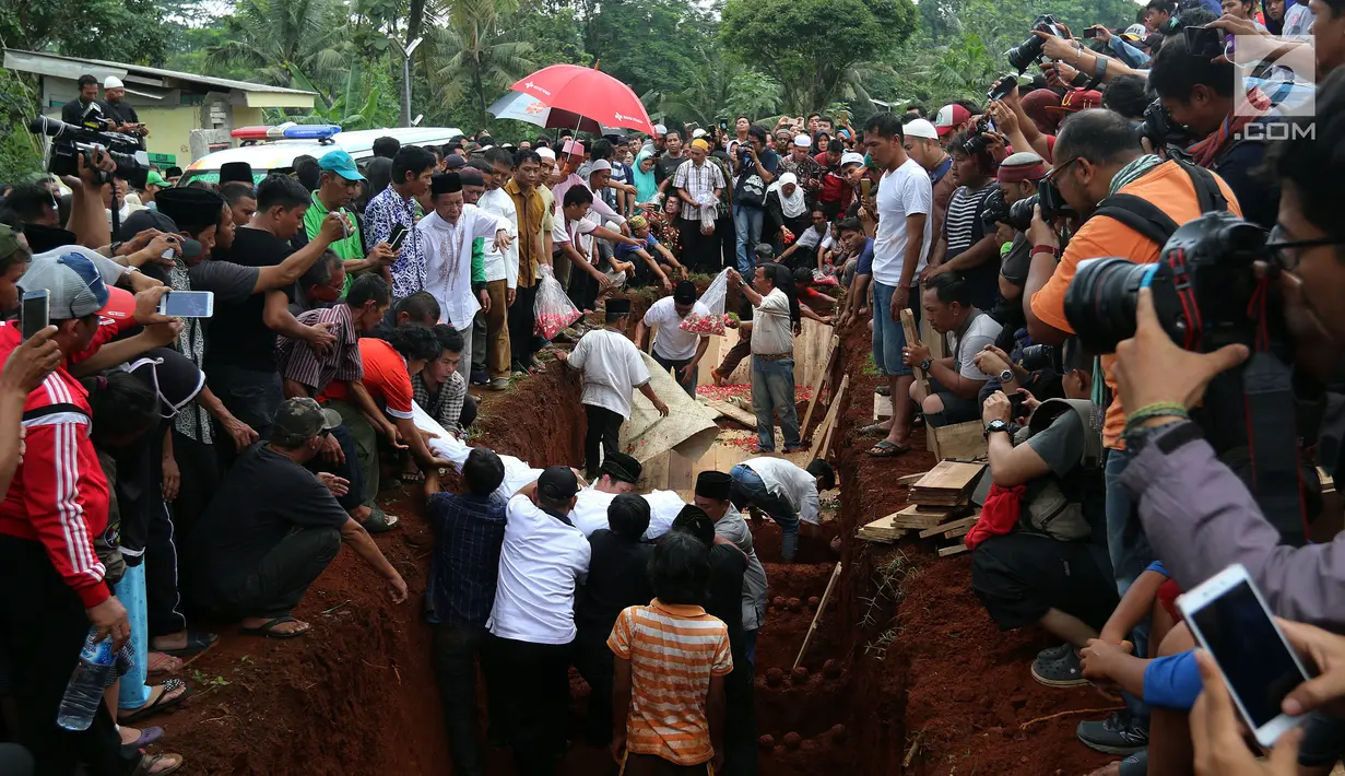 Penurunan jenazah ke liang lahat saat pemakaman korban kecelakaan bus di Tanjakan Emen Subang di TPU Legoso Ciputat, Tangerang Selatan, Banten, Minggu (11/2). Sebanyak 26 korban tewas adalah warga Tangerang Selatan. (Liputan6.com/JohanTallo)