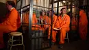 Para pengunjung duduk dalam sel mereka di bar koktail Alcotraz di London Timur, 11 Oktober 2018. Pengunjung harus mengganti pakaian mereka dengan baju tahanan berwarna oranye untuk memasuki bar berkonsep penjara ini. (BEN STANSALL / AFP)