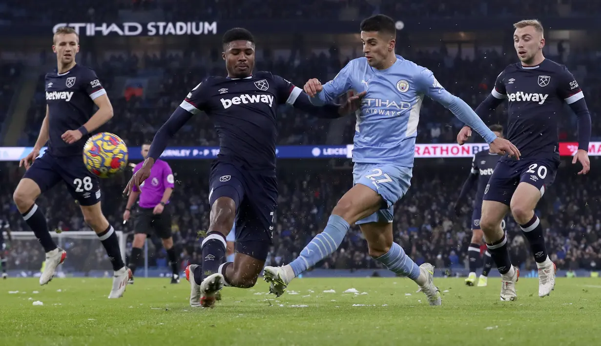 Bek Manchester City, Joao Cancelo mengumpan bola dari kawalan pemain West Ham United, Ben Johnson pada pertandingan lanjutan Liga Inggris di stadion Etihad, Inggris, Minggu (28/11/2021). City menang tipis atas West Ham 2-1. (AP Photo/Scott Heppell)