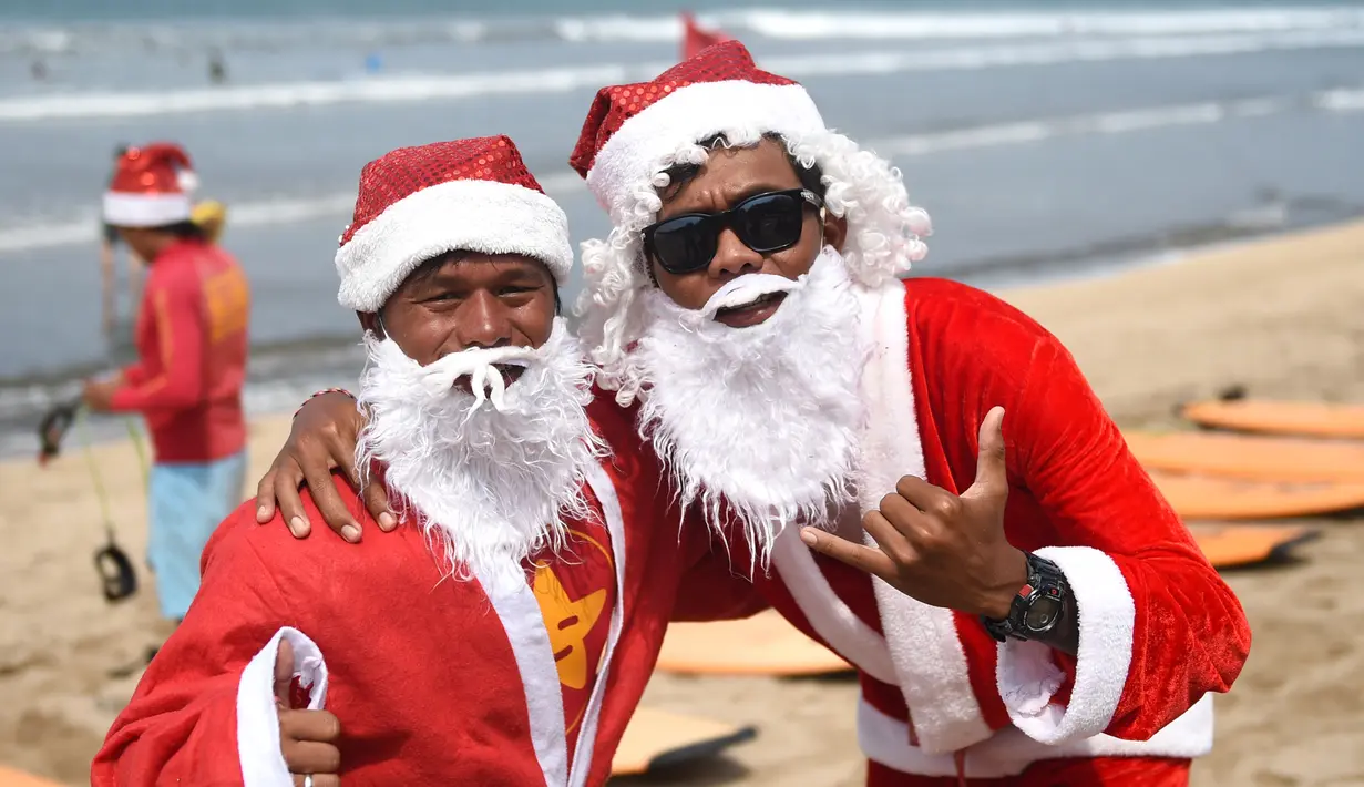 Dua orang pria berpose dengan mengenakan kostum Santa Claus di Pantai Kuta, Bali, Senin (10/12). Setiap tahunnya, ribuan wisatawan mendatangi Bali saat menjelang natal dan tahun baru. (AFP PHOTO / Sonny Tumbelaka)