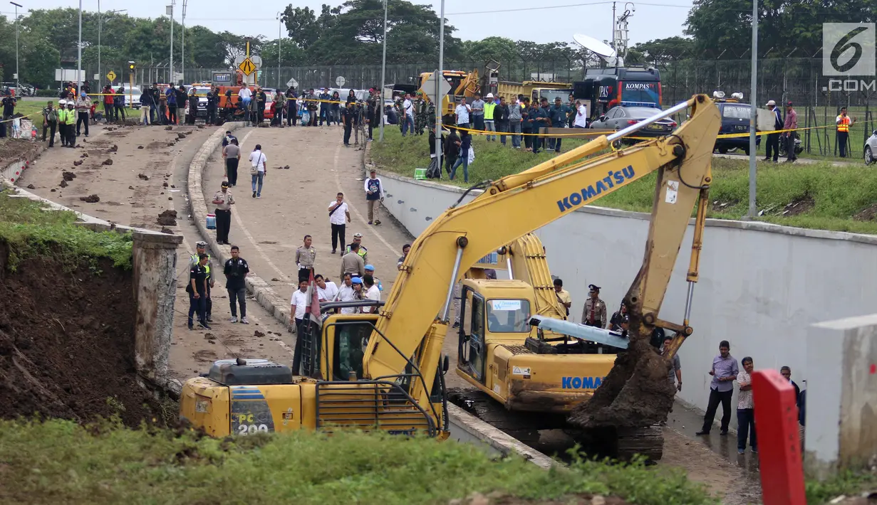 Suasana proses evakuasi mobil yang tertimbun longsor di Underpass Perimeter, Bandara Soetta, Tangerang, Banten, Selasa (6/2). Selain membersihkan longsor, alat berat juga dikerahkan untuk mengevakuasi mobil yang tertimbun. (Liputan6.com/Angga Yuniar)