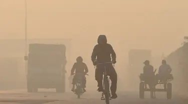 Pengendara melintas di sepanjang jalan di tengah kondisi kabut asap di Lahore, Pakistan (23/11/2021). Kondisi kabut asap yang memburuk membuat Lembaga pendidikan, kantor swasta tutup selama tiga hari seminggu di Lahore. (AFP/Arif Ali)