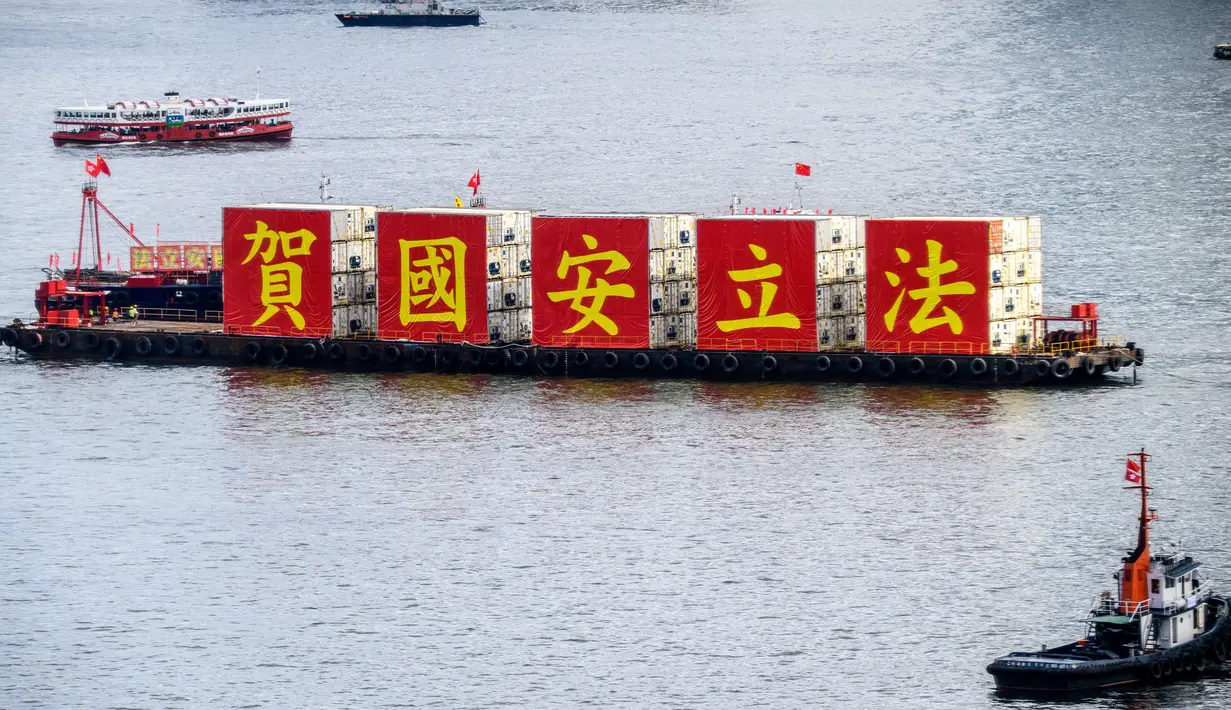 Kapal tongkang dengan spanduk bertuliskan “Rayakan Hukum Keamanan Nasional” berlayar di Victoria Harbour pada peringatan 23 tahun penyerahan Hong Kong dari Inggris ke China di Hong Kong, Rabu (1/7/2020). Hong Kong menandai 23 tahun penyerahan dari Inggris ke Cina pada 1 Juli. (Anthony WALLACE/AFP)