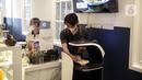 Pegawai menaruh pesanan pada robot pelayan untuk diantar kepada pelanggan di Rasa Koffie, Pasar Baru, Jakarta, Kamis (13/1/2022). Robot tersebut telah diprogram sesuai dengan meja yang tersedia. (Liputan6.com/Faizal Fanani)