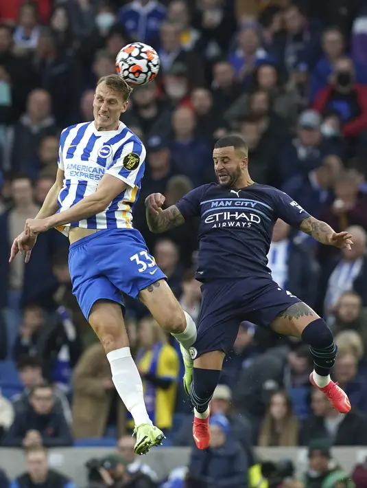 Bek Manchester City, Kyle Walker berebut bola udara dengan pemain Brighton and Hove Albion, Dan Burn pada pertandingan lanjutan Liga Inggris di Stadion AMEX, London, Sabtu (23/10/2021). Kemenangan atas Brighton membuat City naik ke peringkat kedua klasemen. (Gareth Fuller/PA via AP)