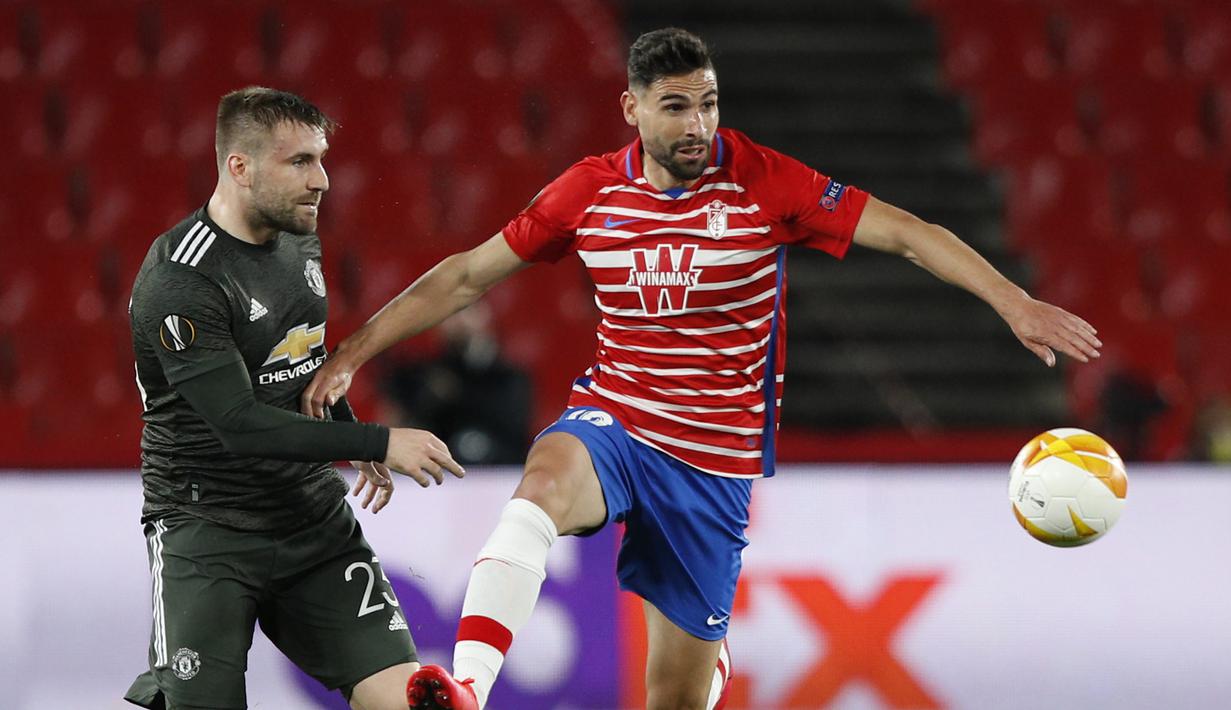 Gelandang Granada, Antonio Puertas (kanan) menguasai bola dibayangi bek Manchester United, Luke Shaw dalam laga leg pertama perempatfinal Liga Europa 2020/2021 di Nuevo Los Carmenes Stadium, Granada, Kamis (8/4/2021). Granada kalah 0-2 dari Manchester United. (AP/Fermin Rodriguez)