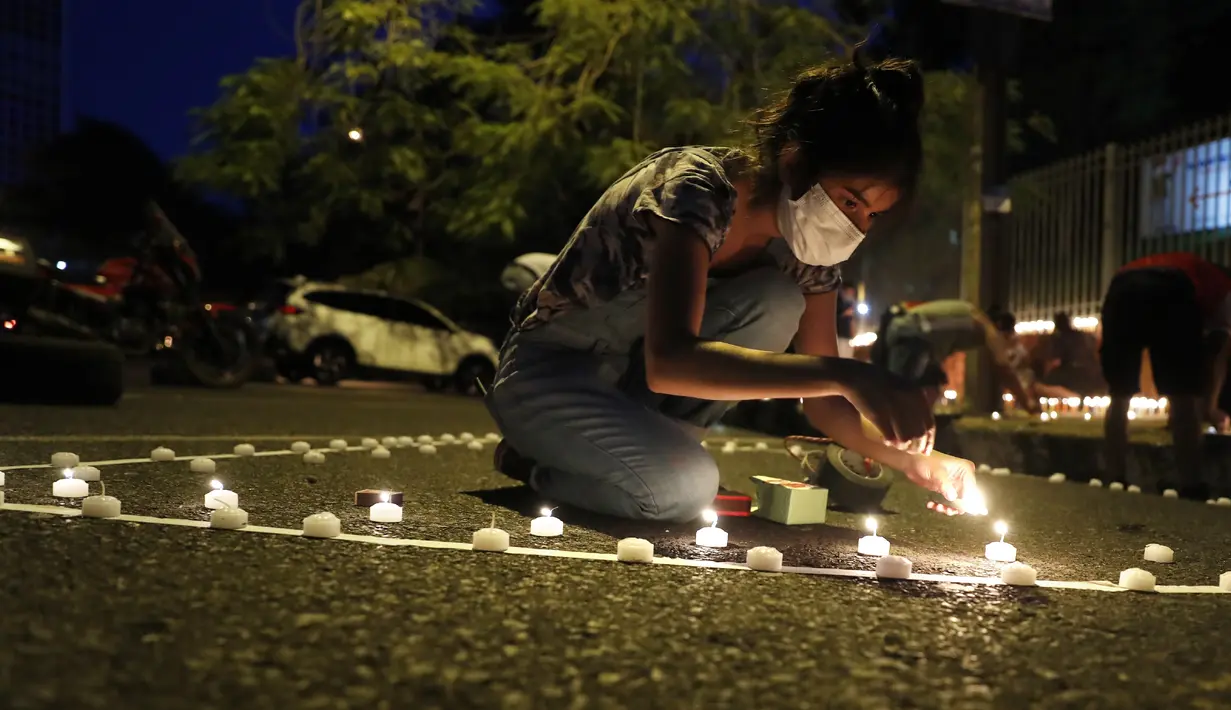 Belen Nunez menyalakan lilin untuk mengenang mereka yang meninggal akibat virus corona di depan Kementerian Kesehatan di Asuncion, Paraguay, Minggu (14/3/2021). Sejuah ini, Paraguay mencatat 3.450 kasus kematian akibat COVID-19. (AP Photo/Jorge Saenz)