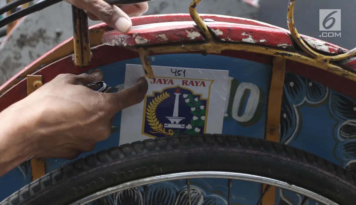 Petugas menempelkan stiker berlogo Pemprov DKI pada becak seusai dilakukan pendataan di Kolong Flyover Bandengan Utara, Jakarta, Kamis (25/1). Pendataan terkait rencana Pemprov DKI Jakarta melegalkan operasional becak. (Liputan6.com/Arya Manggala)