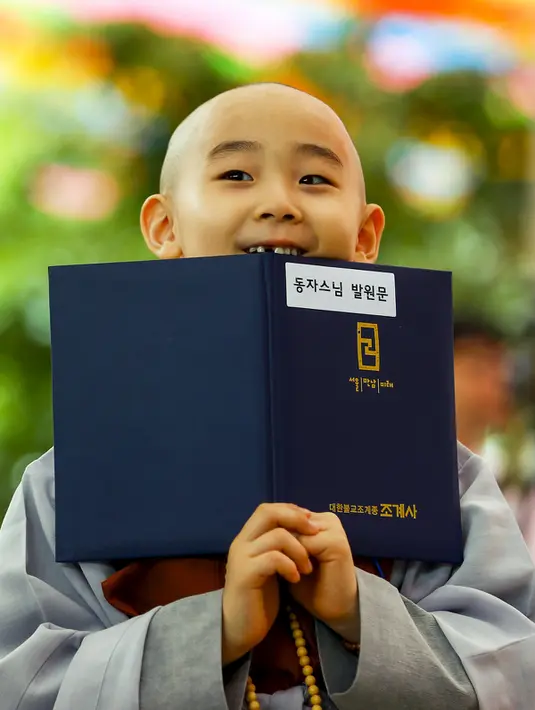 Seorang biksu pemula memegang buku  saat upacara pemberkatan Biksu di kuil Jogye, Seoul, Senin (11/5/2015). Sepuluh orang anak diberikan kesempatan untuk mengalami kehidupan sebagai biksu selama dua minggu. (REUTERS/Thomas Peter)
