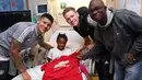 Pemain Manchester United, Marcos Rojo (kiri) dan rekan-rekannya melakukan sesi foto dengan pasien Rumah Sakit Anak saat membagikan kebahgiaan jelang Natal di Manchester, (18/12/2017). (Bola.com/Dok.Manutd.com)