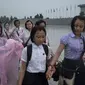 Para siswa tengah berjalan meski hujan deras untuk memberi penghormatan kepada mantan pemimpin Korea Utara Kim Il Sung dan Kim Jong-Il di luar Istana Kumsusan saat negara tersebut menandai 'Hari Kemenangan' di Pyongyang (AFP/Ed JONES)