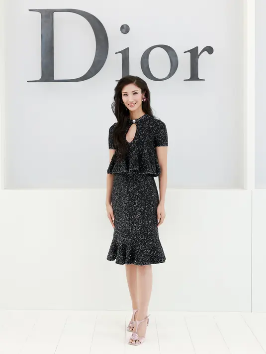 Ejae tampil berkilau dengan atasan peplum dan rok midi bertabur glitter hitam-putih. Dilengkapi anting bunga warna-warni dan heels pink berhias bunga. [dok. Dior]