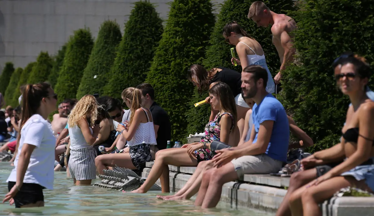 Sejumlah orang menyegarkan diri di air mancur Trocadero, Paris, sambil menikmati matahari musim panas, Senin (19/6). Suhu temperatur di ibu kota Prancis ini mencapai 36 derajat celcius. (AFP Photo / LUDOVIC MARIN)