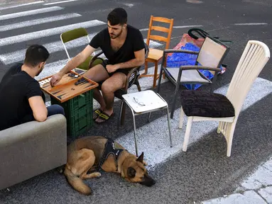 Warga bermain backgammon di jalan bebas mobil saat Hari Raya Yom Kippur di Ramat Gan, Israel, Kamis (16/9/2021). Yom Kippur atau Hari Penebusan Dosa merupakan hari raya paling suci umat Yahudi dimana mereka akan berhenti beraktivitas secara total. (AP Photo/Oded Balilty)