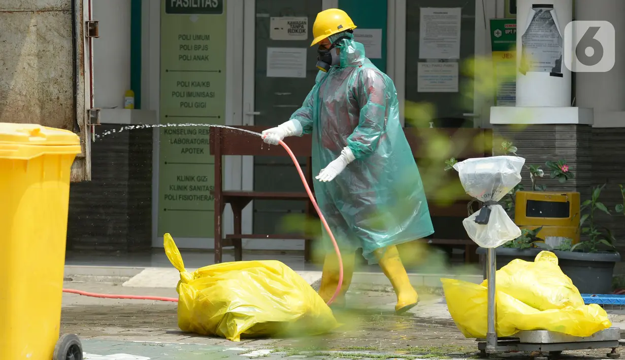 Petugas kesehatan memakai baju APD sedang membersihkan sampah bekas medis di Puskesmas Pamulang, Kecamatan Pamulang, Tangerang Selatan, Banten, Senin (13/04/2020). Sampah bekas medis tes Covid-19 tersebut akan dimusnahkan guna untuk mensteril kawasan puskesmas. (merdeka.com/Dwi Narwoko)