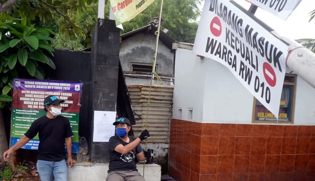 Sejumlah pemuda menjaga portal karantina wilayah menuju RW 10 di kawasan Tanah Kusir, Kelurahan Kebayoran Lama Selatan, Jakarta, Rabu (8/4/2020). Warga menerapkan akses satu pintu masuk pemukiman yang terdiri dari 12 RT tersebut untuk mencegah penyebaran corona COVID-19. (merdeka.com/Dwi Narwoko)