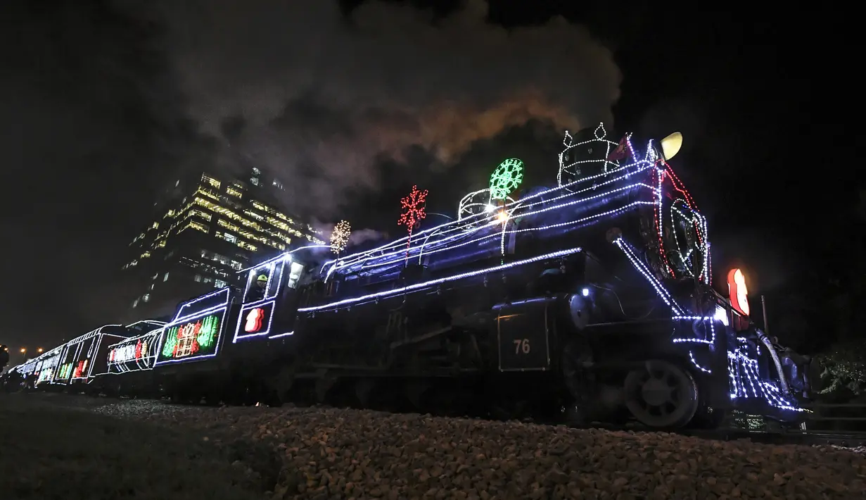 Kereta wisata yang dihiasi lampu Natal terlihat di Bogota (20/12/2019). Meyambut Hari Natal, kereta wisata di Kolombia membuat cara unik dengan memasangkan lampu warna-warni agar menjadi daya tarik penumpang. (AFP Photo/Juan Barreto)