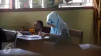 Seorang peserta membawa anaknya saat mengikuti ujian kesetaraan Paket C di SMPN 15 Yogyakarta, Senin (4/4). Sebanyak 447 peserta mengikuti ujian akhir untuk mendapatkan ijazah setingkat SMA. (Liputan6.com/Boy Harjanto)