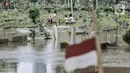 Anak-anak bermain saat banjir merendam TPU Karet Bivak, Jakarta, Minggu (7/2/2021). Banjir yang terjadi di TPU Karet Bivak untuk kedua kalinya tersebut juga menyulitkan mereka yang ingin melakukan ziarah ke makam keluarga maupun kerabat. (merdeka.com/Iqbal Nugroho)