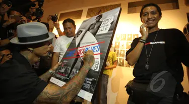 Drummer grup musik Superman Is Dead, Jrx (kiri) menandatangani foto saat pameran fotografi "Laut Luka Blues" di Galeri Foto Jurnalistik Antara , Jakarta, Jumat (22/5/2015). 51 karya foto karya Ismar Patrizki dipamerkan. (Liputan6.com/Faizal Fanani)