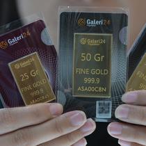 Seorang karyawan menunjukkan emas batangan 25, 50, dan 100 gram produksi Galeri 24, anak perusahaan dari PT Pegadaian (Persero), di Jakarta pada 14 April 2025. (BAY ISMOYO/AFP)