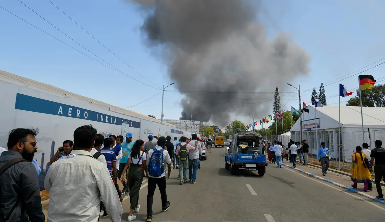 Asap hitam kebakaran mobil terlihat dari pameran dirgantara Aero India 2019, Bangalore, India, Sabtu (23/2). Api yang melahap sekitar 300 mobil diduga akibat rumput kering yang terbakar. (STR/AFP)