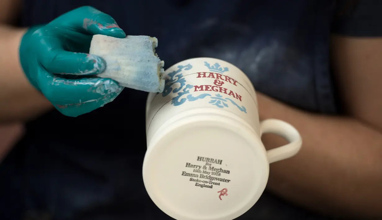 Seorang pekerja melukis dengan tangan sebuah mug untuk merayakan pernikahan Pangeran Harry dan Meghan Markle di pabrik Emma Bridgewater di Stoke-on-Trent, Inggris (16/4). (AFP/Oli Scarff)