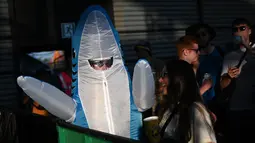 Seorang pengunjung festival yang mengenakan pakaian hiu menonton para penampil  di kawasan Silver Hayes pada hari ke-2 festival Glastonbury di desa Pilton di Somerset, Inggris barat daya, pada 22 Juni 2023. Festival ini berlangsung dari 21 Juni hingga 26 Juni. (Photo by Oli SCARFF / AFP)