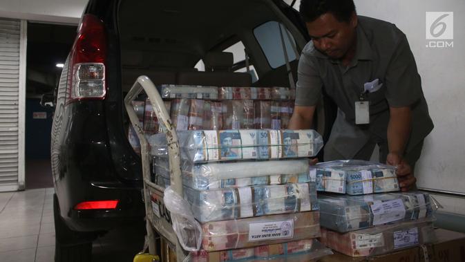 Petugas memasukkan lembaran uang rupiah ke dalam mobil di Bank Mandiri, Jakarta, Kamis (21/12). Guna memenuhi kebutuhan uang tunai selama perayaan Natal dan Tahun Baru 2018, BI menyiapkan uang kartal sebanyak Rp 193,9 triliun. (Liputan6.com/Angga Yuniar)