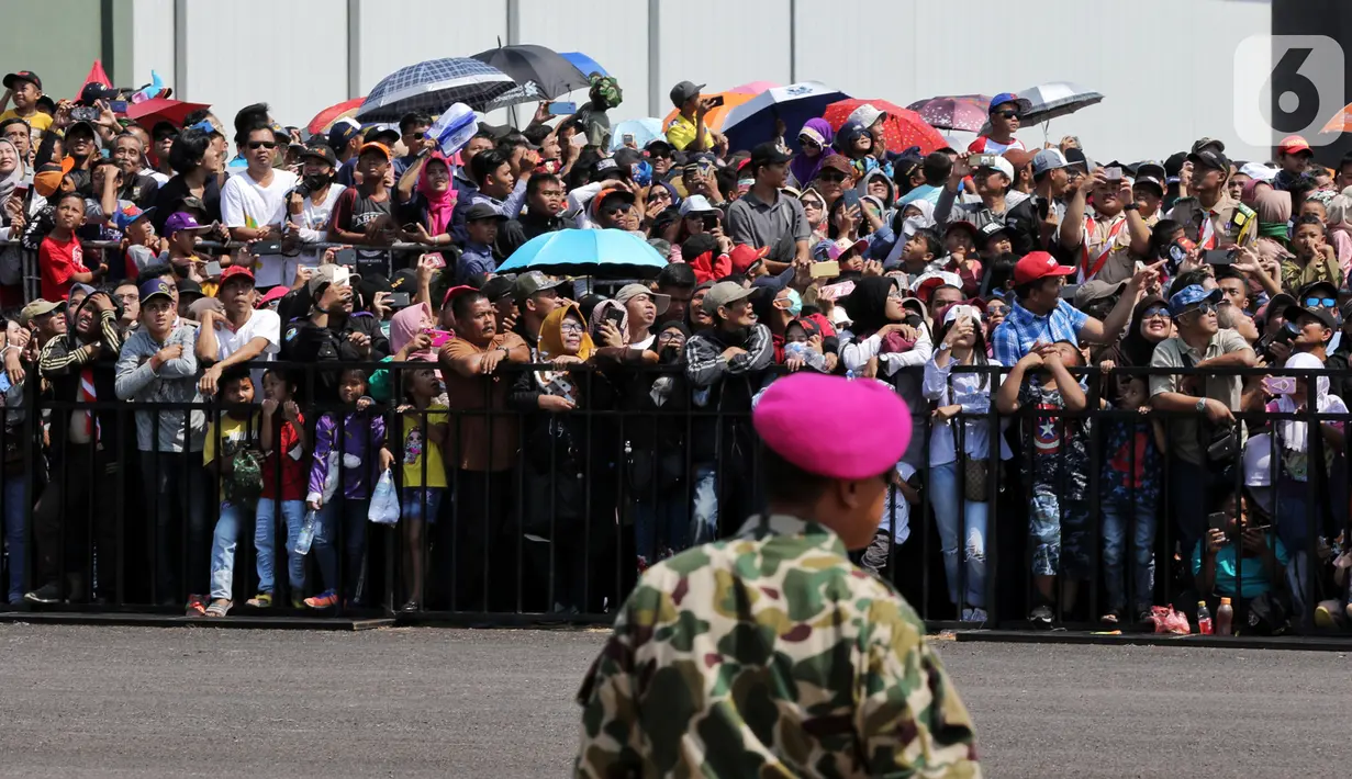Antusiasme warga saat menyaksikan perayaan HUT ke-74 TNI di Lanud Halim Perdanakusuma, Jakarta Timur, Sabtu (5/10/2019). Warga rela panas-panasan dan berdesak-desakan untuk menyaksikan perayaan HUT ke-74 TNI. (Liputan6.com/JohanTallo)