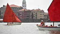 Anggota asosiasi pelayaran budaya berlayar dalam acara Regatta Merah di Venesia, Italia, Minggu (20/6/2021). Acara ini bertujuan untuk merayakan tradisi bahari Venesia kuno dan untuk meningkatkan kesadaran tentang keseimbangan antara kota dan laut. (MARCO BERTORELLO/AFP)