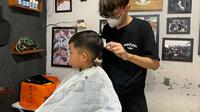 Salah satu anggota Persaudaraan Pangkas Rambut Garut (PPRG) Garut, tengah memberikan pelayan jasa potong rambut kepada pelanggan. (liputan6.com/Jayadi Supriadin)