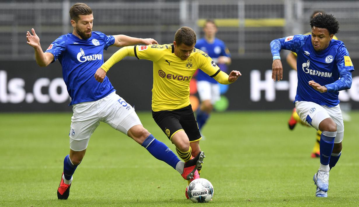 Pemain Borussia Dortmund, Thorgan Hazard, berusaha melewati pemain Schalke 04 pada laga Bundesliga di Stadion Signal Iduna Park, Sabtu (16/5/2020). Dortmund menang 4-0 atas Schalke 04. (AP/Martin Meissner)
