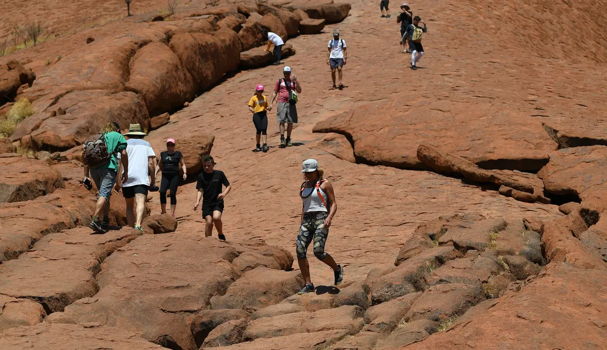 Wisatawan mendaki Uluru yang juga dikenal sebagai Batu Ayers di Taman Nasional Uluru-Kata Tjuta, utara Australia, Jumat (25/10/2019). Pendakian di Batu Ayers tersebut akan dilarang pada Oktober ini, seiring dengan keinginan Anagu, suku asli Aborigin yang mendiami kawasan tersebut. (SAEED KHAN / AFP)
