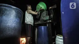 Pekerja menuang kedelai rebus saat proses pembuatan tempe di kawasan Sunter, Jakarta, Senin (4/1/2021). Perajin tempe setempat berupaya mengurangi kerugian akibat melonjaknya harga kedelai impor dengan memperkecil ukuran tempe dan menaikan harga jual. (merdeka.com/Iqbal S. Nugroho)