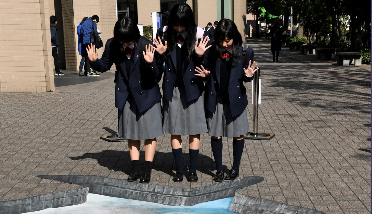 Sejumlah siswa berpose di depan karya ilusi optik bergambar kota Aleppo yang hancur akibat perang di kampus Universitas Meiji di Tokyo, Jepang (18/11). Karya ini mendorong agar para siswa ikut prihatin terkait perang di Suriah. (AFP/Toshifumi Kitamura)