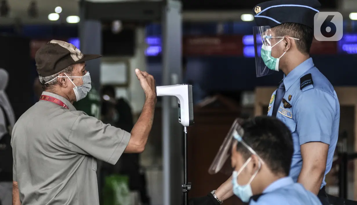 Calon penumpang memeriksa suhu tubuh sebelum check in di Bandara Halim Perdanakusuma, Jakarta, Kamis (17/12/2020). Pemerintah mewajibkan penumpang yang ingin keluar masuk Jakarta untuk melakukan rapid test antigen mulai 18 Desember 2020 - 8 Januari 2021. (merdeka.com/Iqbal Nugroho)