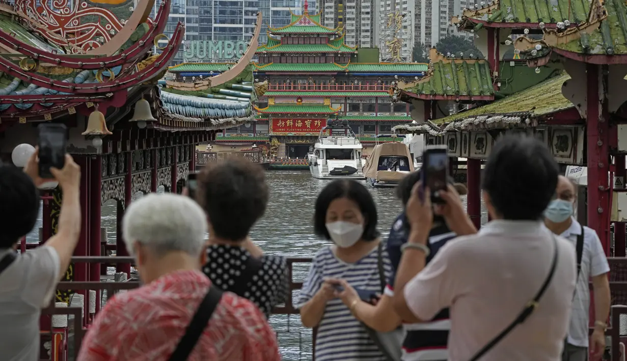 Turis mengambil foto Restoran Terapung Jumbo yang ikonik di Hong Kong, Senin (13/6/2022). Pemimpin Hong Kong Carrie Lam sebelumnya mengatakan bahwa pihak berwenang tidak akan menyelamatkan restoran, meskipun ada seruan dari anggota parlemen untuk melestarikan landmark ikonik tersebut. (AP Photo/Kin Cheung)