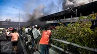 Sejumlah warga menonton petugas pemadam kebakaran yang tengah berusaha memadamkan api yang melahap pusat perbelanjaan Blok III Pasar Senen, Jakarta Pusat, Kamis (19/1). (Liputan6.com/Faizal Fanani)