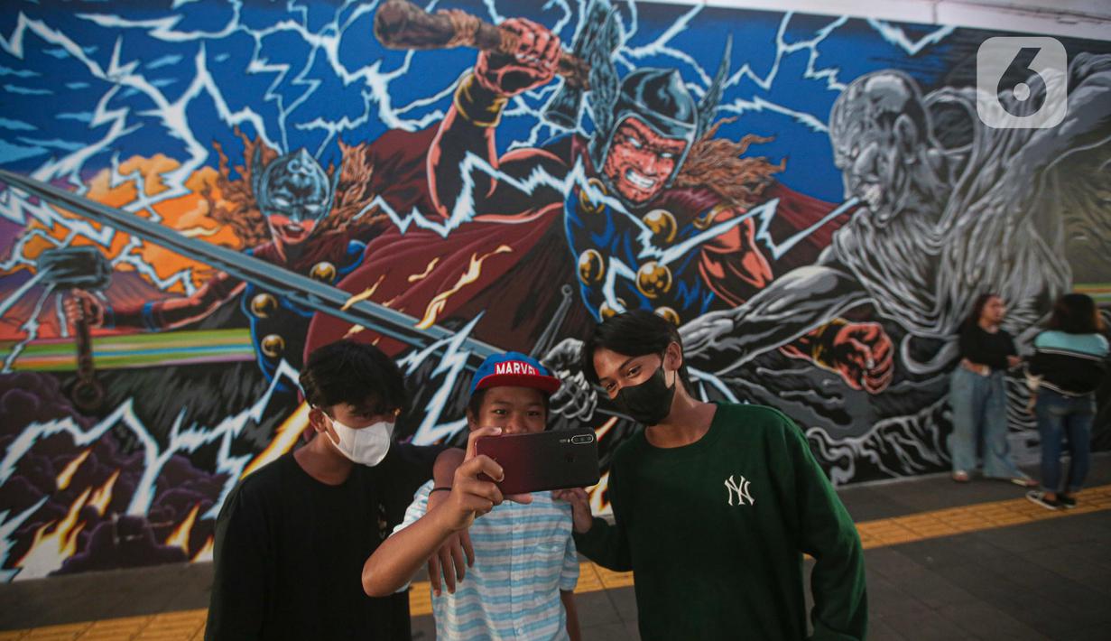 Warga berswafoto dengan latar belakang mural kolaborasi di Terowongan Kendal, Kawasan TOD Dukuh Atas, Jakarta, Rabu (6/7/2022). Disney Indonesia berkolaborasi bersama Jakarta Experience Board (JXB) dan Kita Art Friends menghadirkan karya seni mural terinspirasi dari film Marvel Studios "Thor: Love and Thunder." (Liputan6.com/Faizal Fanani)