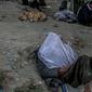 Seorang pria tidur di pinggir jalan saat orang lain mengonsumsi narkoba di Kabul,  Afghanistan, 21 September 2021. Afghanistan dikenal sebagai penghasil opium nomor satu di dunia. (BULENT KILIC/AFP)