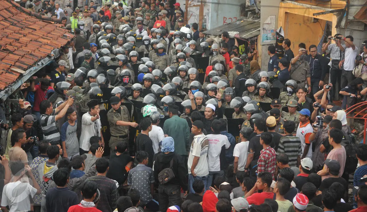 Warga mencoba menghalangi petugas yang akan melakukan penggusuran di Pasar Ikan, Penjaringan, Jakarta, Senin (11/4). Penertiban sempat diwarnai bentrokan antara petugas dan warga yang menolak penggusuran di kawasan tersebut. (Liputan6.com/Gempur M Surya)