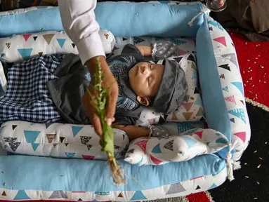 Orang-orang berdoa untuk bayi yang baru lahir saat prosesi aqiqah di Banda Aceh, Aceh, 4 November 2021. Aqiqah adalah tradisi menyambut bayi yang baru lahir dalam agama Islam. (CHAIDEER MAHYUDDIN/AFP)