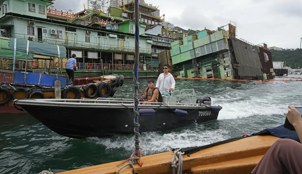 Sebuah perahu bergerak melewati bagian dapur yang tenggelam, di belakang kanan, yang merupakan bagian dari Restoran Terapung Jumbo Hong Kong bergaya kekaisaran Cina terakhir, di Hong Kong, Senin (13/6/2022). (AP Photo/Kin Cheung)