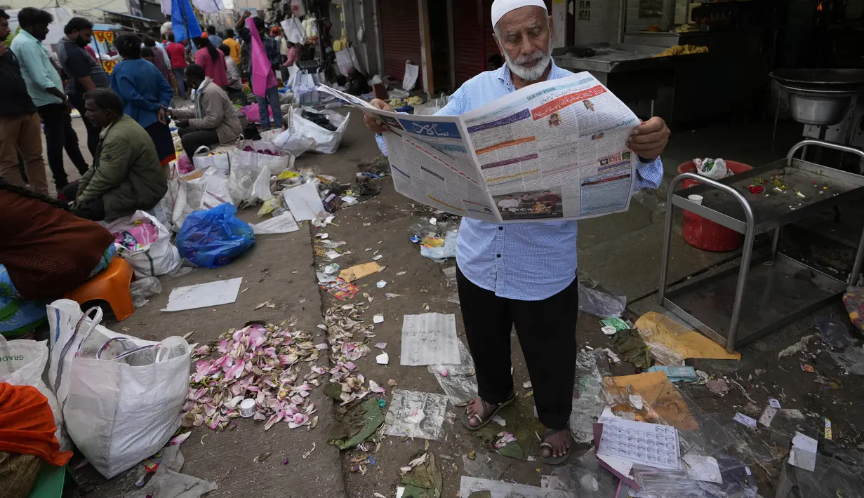 Seorang pria membaca koran di pasar grosir di Bengaluru, India, Rabu (13/4/2022). Orang-orang telah kembali beraktivitas normal setelah pihak berwenang mencabut pembatasan COVID-19 termasuk mengenakan masker wajah di tempat-tempat umum. (AP Photo/Aijaz Rahi)