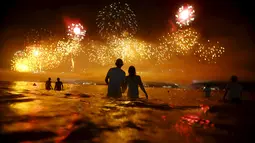 Sejumlah orang saat menyaksikan kembang api di pantai Copacabana saat perayaan Tahun Baru 2016 di Rio de Janeiro, Brasil, (1/1/2016). (REUTERS/Ricardo Moraes)