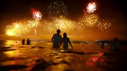 Sejumlah orang saat menyaksikan kembang api di pantai Copacabana saat perayaan Tahun Baru 2016 di Rio de Janeiro, Brasil, (1/1/2016). (REUTERS/Ricardo Moraes)