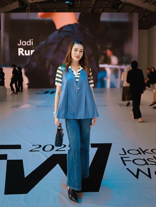 Aaliyah Massaid tampil stylish dengan gaya denim on denim yang memukau di Jakarta Fashion Week 2025. Ia memadukan atasan stripe tee dengan vest denim berpotongan longgar, serta celana jeans berpotongan lebar. Sepatu pointed-toe dan tas Dior hitam semakin menambah kesan edgy pada tampilannya. [@aaliyah.massaid].