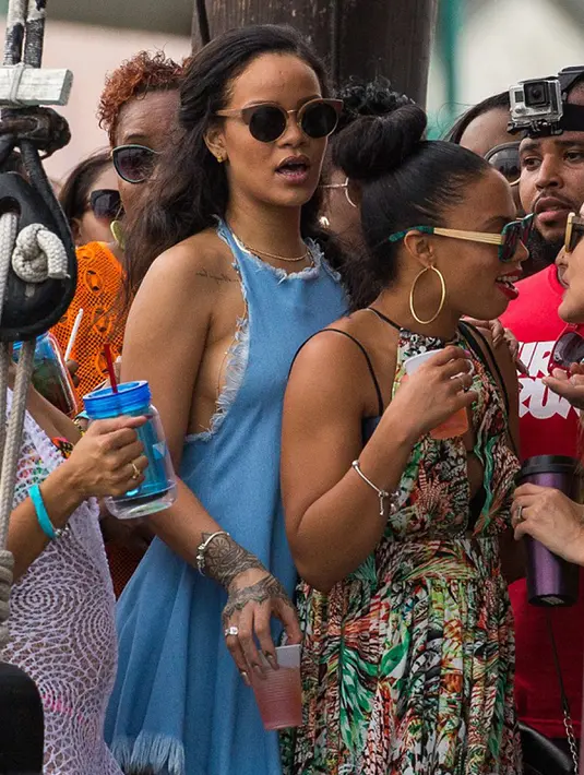 Rihanna dan temannya saat menikmati liburan di sebuah pantai di Barbados pada 26 Desember 2015 lalu. Mantan kekasih Chris Brown itu terlihat seksi dalam balutan dress biru hingga payudaranya terlihat menonjol karena tak mengenakan bra. (www.thesun.co.uk)